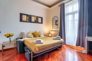 A modern hotel room with a bed, bedside table, and a window with curtains.