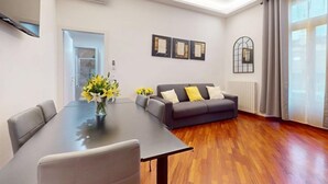 Uma sala de estar moderna com uma mesa de jantar, sofá cinza e obras de arte na parede.