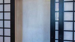 Quarto com porta deslizante, parede com padrão listrado vertical e suporte branco suspenso.
