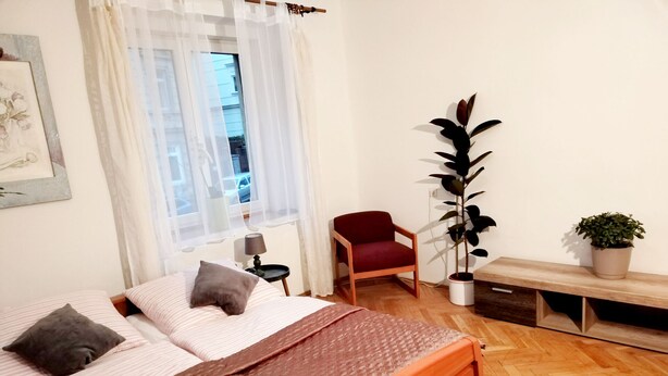 Een slaapkamer met een bed, een stoel, een plant en een bank.
