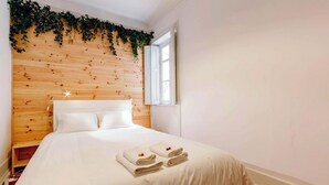 A hotel room with a wooden headboard, a bed with white linens, and a window with a view. - The Palm Leaf SOC in Lisboa Ciudad (Lisbon)