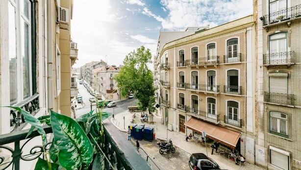 A street view with buildings, a tree, and parked cars. - The Palm Leaf SOC in Lisboa Ciudad (Lisbon)