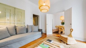 A modern living room with a grey sofa, a wooden coffee table, and a wicker chair. - The Palm Leaf SOC in Lisboa Ciudad (Lisbon)