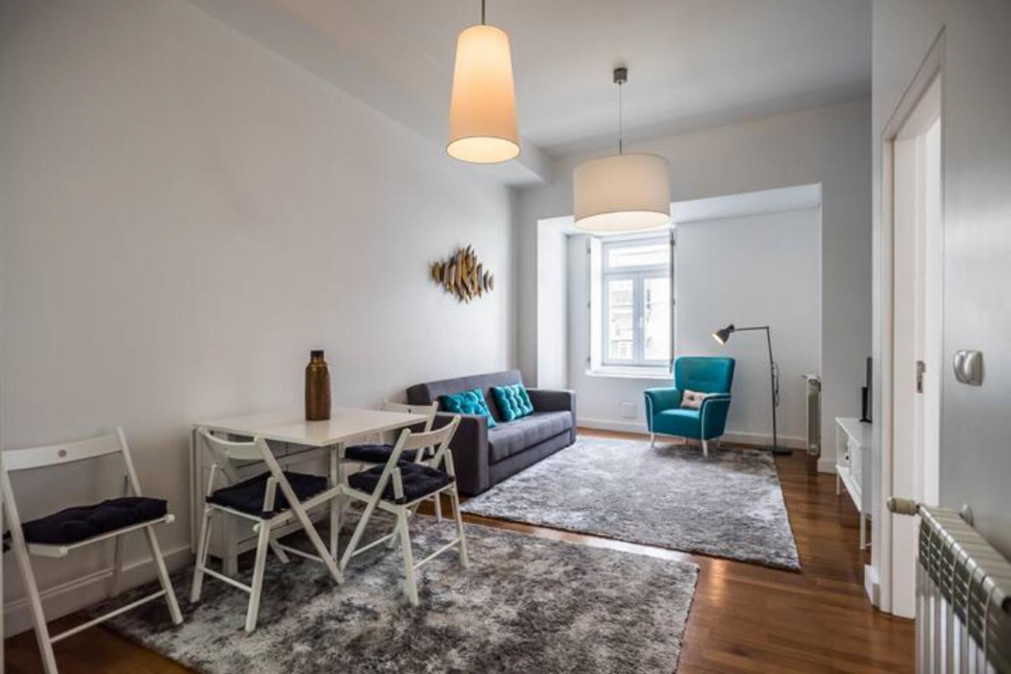 Una sala moderna con un sofá, una mesa de comedor con sillas y un sillón azul.