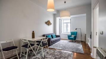 Una sala moderna con un sofá, una mesa de comedor con sillas y un sillón azul.