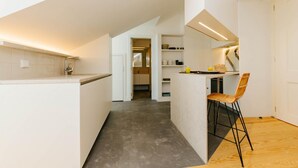 Une cuisine moderne dotée d’un îlot central, d’un coin repas avec une chaise, et offrant une vue sur la salle à manger adjacente.