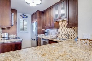 A kitchen with granite countertops, stainless steel appliances, and wooden cabinets.