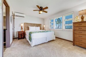 A bedroom with a bed, a ceiling fan, a nightstand, a dresser, and a window with blinds.