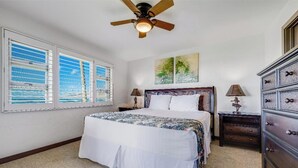 A bedroom with a bed, two nightstands, a dresser, a ceiling fan, and a window with blinds.