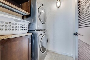 A laundry area with a washing machine and dryer, a wooden cabinet, and a white laundry basket.