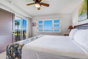A bedroom with a bed, a ceiling fan, a window with blinds, and a door leading to a balcony.