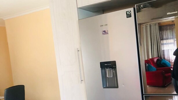 Ett modernt kök med ett kylskåp i rostfritt stål, en vattenautomat och ljusa köksskåp.
