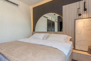 A modern hotel room with a large bed, a built-in curved mirror, and a minimalist decor. - Luxury Villa Hera in Vodice (Srima)