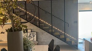 A modern interior with a wooden staircase, a perforated black partition, and a potted plant. - Luxury Villa Hera in Vodice (Srima)