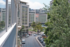 Une rue de la ville avec des bâtiments modernes, un autobus et des voitures garées.