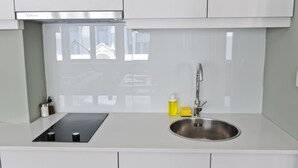 A modern kitchen with white cabinets, a stainless steel sink, and a black induction cooktop.