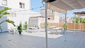An outdoor patio with white furniture, string lights, and a covered seating area.