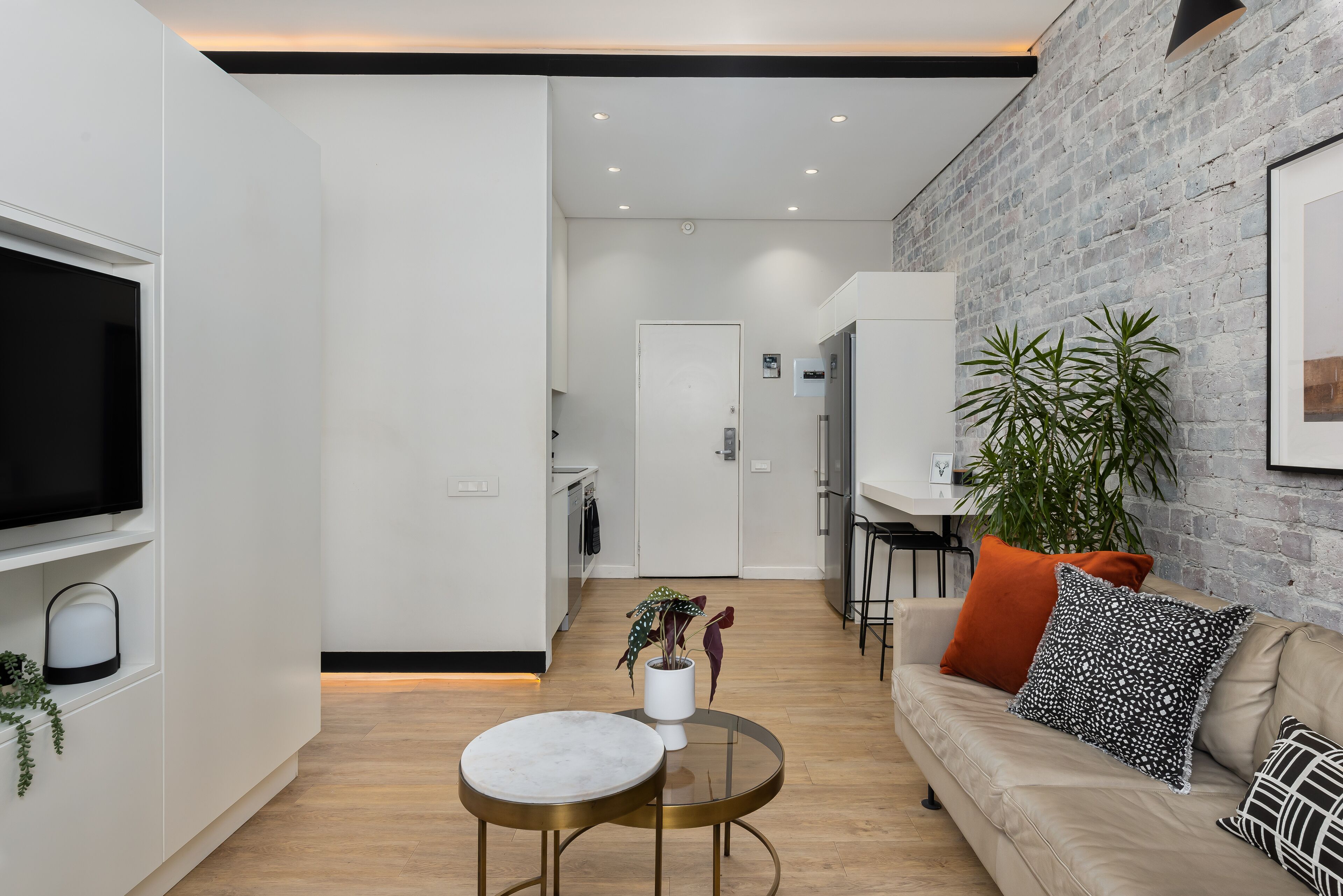 A modern living room with a sofa, a coffee table, a TV, and a kitchen in the background.