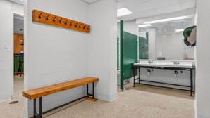 A restroom with a wooden bench, a coat rack, and a sink with a mirror. - Pinnacle A23 (Killington)