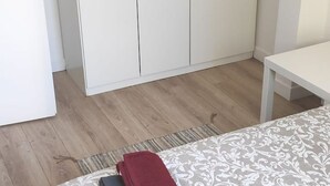 A room with a bed, a white wardrobe, and a small table. - Quiet apartment with balcony (Bois-Colombes)