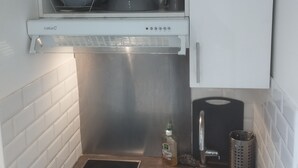 A compact kitchen with a built-in dishwasher, a stainless steel sink, and a compact stove. - Quiet apartment with balcony (Bois-Colombes)