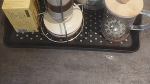 A coffee maker, a kettle, a box of Twinings tea, and a coffee grinder on a black tray. - Quiet apartment with balcony (Bois-Colombes)