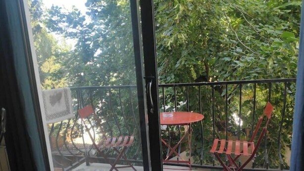 A balcony with a glass door, a small table, and two chairs. - Quiet apartment with balcony (Bois-Colombes)