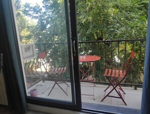 A balcony with a glass door, a small table, and two chairs.