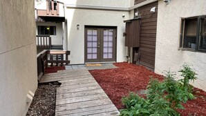 A narrow pathway leading to a door with a small porch area.