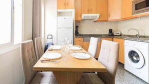 A compact kitchen with wooden cabinets, a built-in microwave, and a washing machine. - Atamanja Beach Apatment Playa de Las Canteras (Palmas De Gran Canaria, Las)