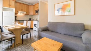 A compact living space with a kitchenette, a dining area, and a gray sofa. - Atamanja Beach Apatment Playa de Las Canteras (Palmas De Gran Canaria, Las)