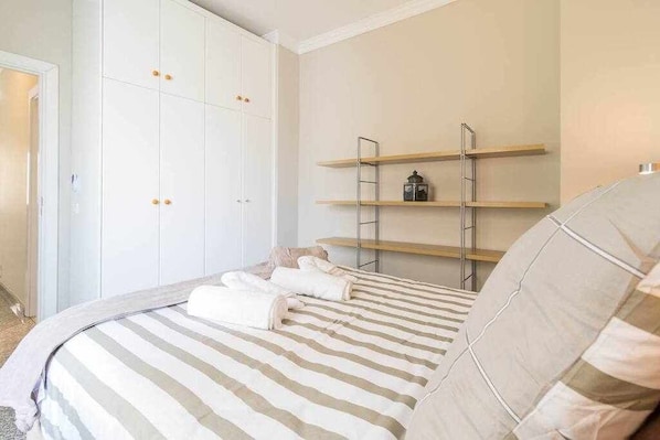 A bedroom with a bed, a wardrobe, and a shelf unit.