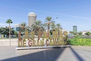 A sign with the text 'Las Palmas de Gran Canaria' surrounded by palm trees and modern buildings.