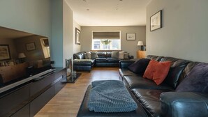 A modern living room with a sofa set, a coffee table, and a flat-screen TV. - Beautiful Two Bedroom Cottage with Amazing Views (Birdsedge)