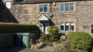 A stone building with a traditional design, featuring a central door, multiple windows, and a satellite dish. - Beautiful Two Bedroom Cottage with Amazing Views (Birdsedge)