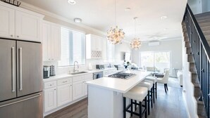 A modern kitchen with white cabinetry, stainless steel appliances, and a central island with bar stools. - 4046 · Modern condo in Hillcrest/Mission Hills (San Diego)
