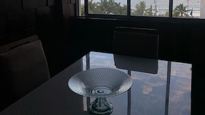 Ein Essbereich mit Tisch und Stühlen, Blick auf das Meer und einer Ziegelwand.
