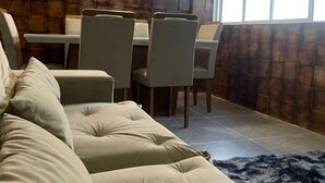 Ein modernes Wohnzimmer mit einer Eckcouch, einem Esstisch mit Stühlen und einem großen Fenster, das für natürliches Licht sorgt.