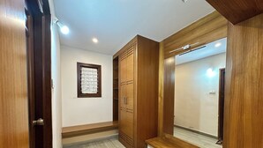 A hallway with wooden doors, a window with blinds, and a mirror on the wall. - Singaras Coffee Country (Ootacamund)