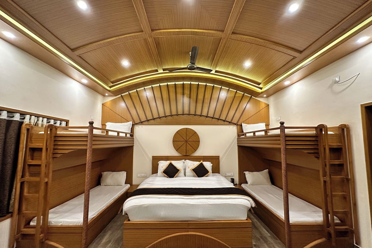 Ein Schlafraum mit Etagenbett, Holzkopfteil und Leiter, einer runden Wanddekoration sowie einer Decke mit Einbaustrahlern.