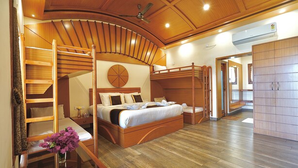 A bedroom with a bunk bed, wooden flooring, a ceiling fan, and a large wardrobe. - Singaras Coffee Country (Ootacamund)