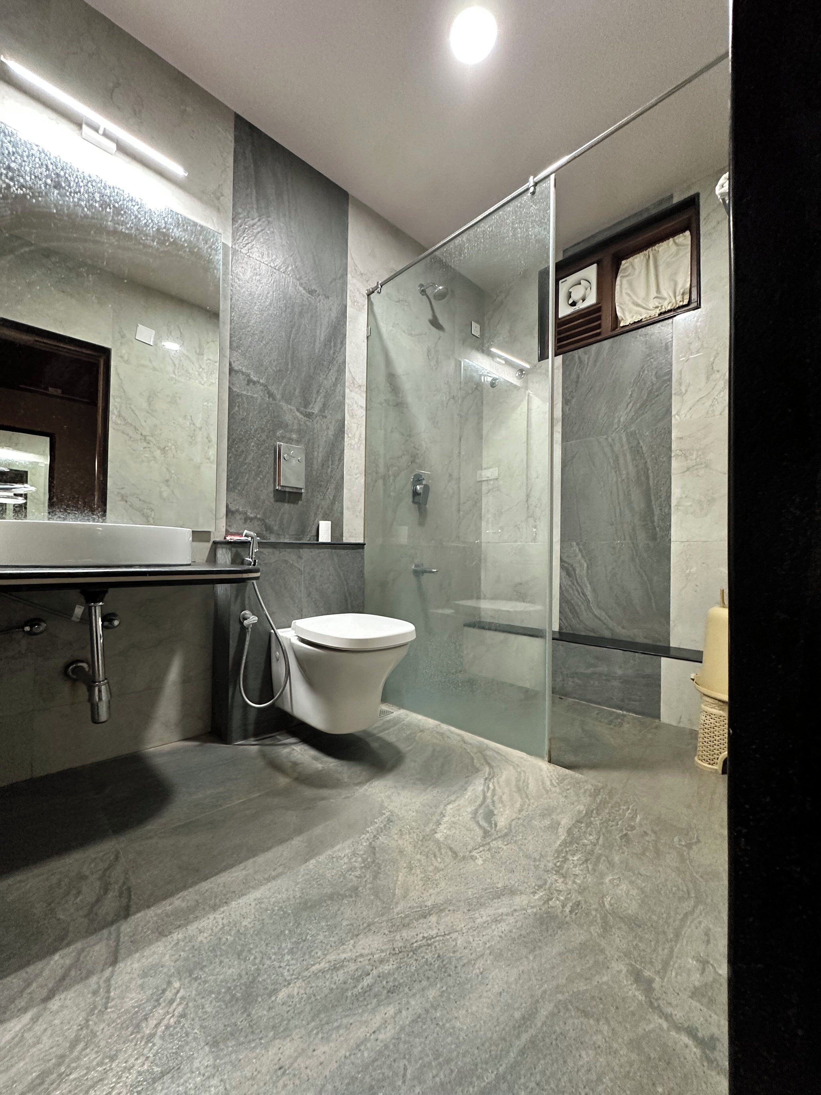 Un baño moderno con ducha de vidrio, inodoro blanco y encimera de mármol.