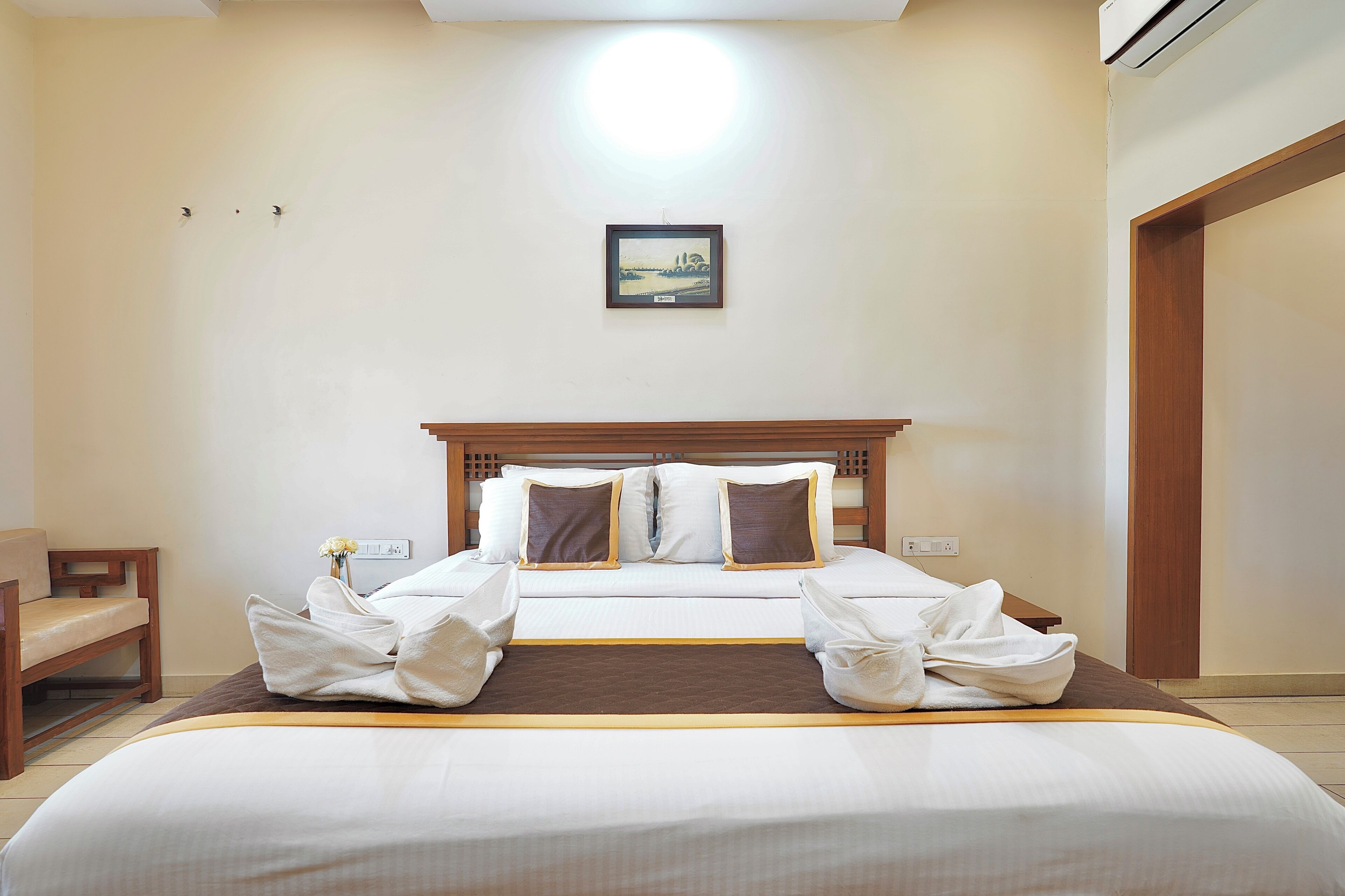 A hotel room with a bed, wooden headboard, and a framed picture on the wall.