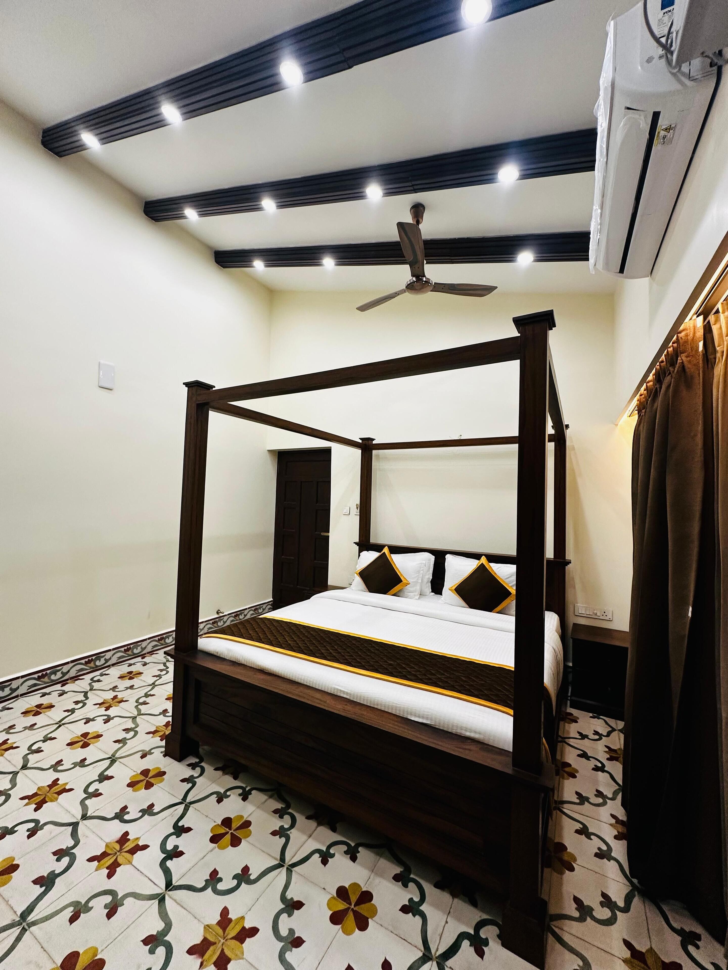 Una cama con dosel con colcha blanca y marrón, un ventilador de techo y un suelo estampado.