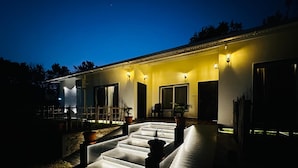 A modern house with a well-lit porch, a staircase leading to the entrance, and a small garden area. - Singaras Coffee Country (Ootacamund)