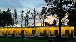 A building with multiple windows and a covered outdoor area with seating. - Singaras Coffee Country (Ootacamund)