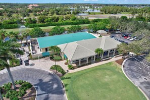 A building with a green roof, surrounded by a parking lot and a golf course. - Cypress Woods for Seasonal or Summer Stays (Naples)