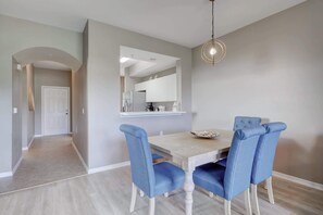 A dining area with a wooden table, blue upholstered chairs, and a pendant light. - Cypress Woods for Seasonal or Summer Stays (Naples)