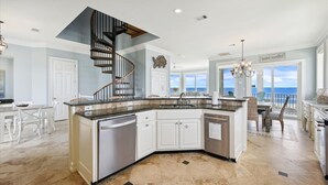 A spacious kitchen with a curved island, a central staircase, and a view of the ocean. - Welcome to Aisle of Palms! (St. George Island)