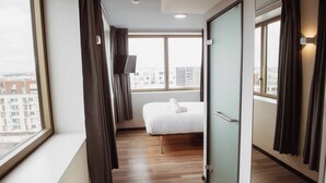 A hotel room with a bed, a window, a TV, and a view of the city.